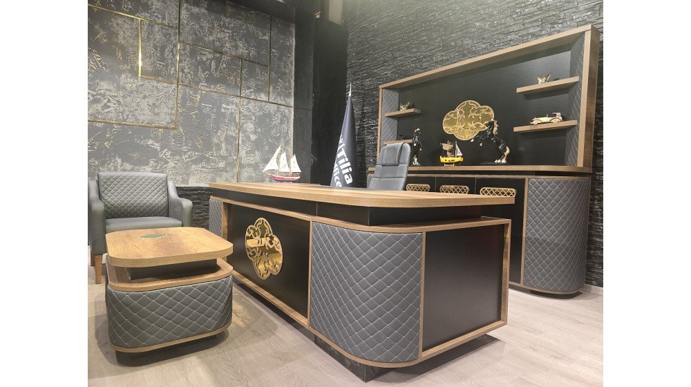 Kemer lüks yönetici masa takımı, gri kapitoneli panelleri, parlak altın rengi lazer kesim metal motifleri ve ceviz rengi tablası ile modern ofis ortamında sergileniyor.